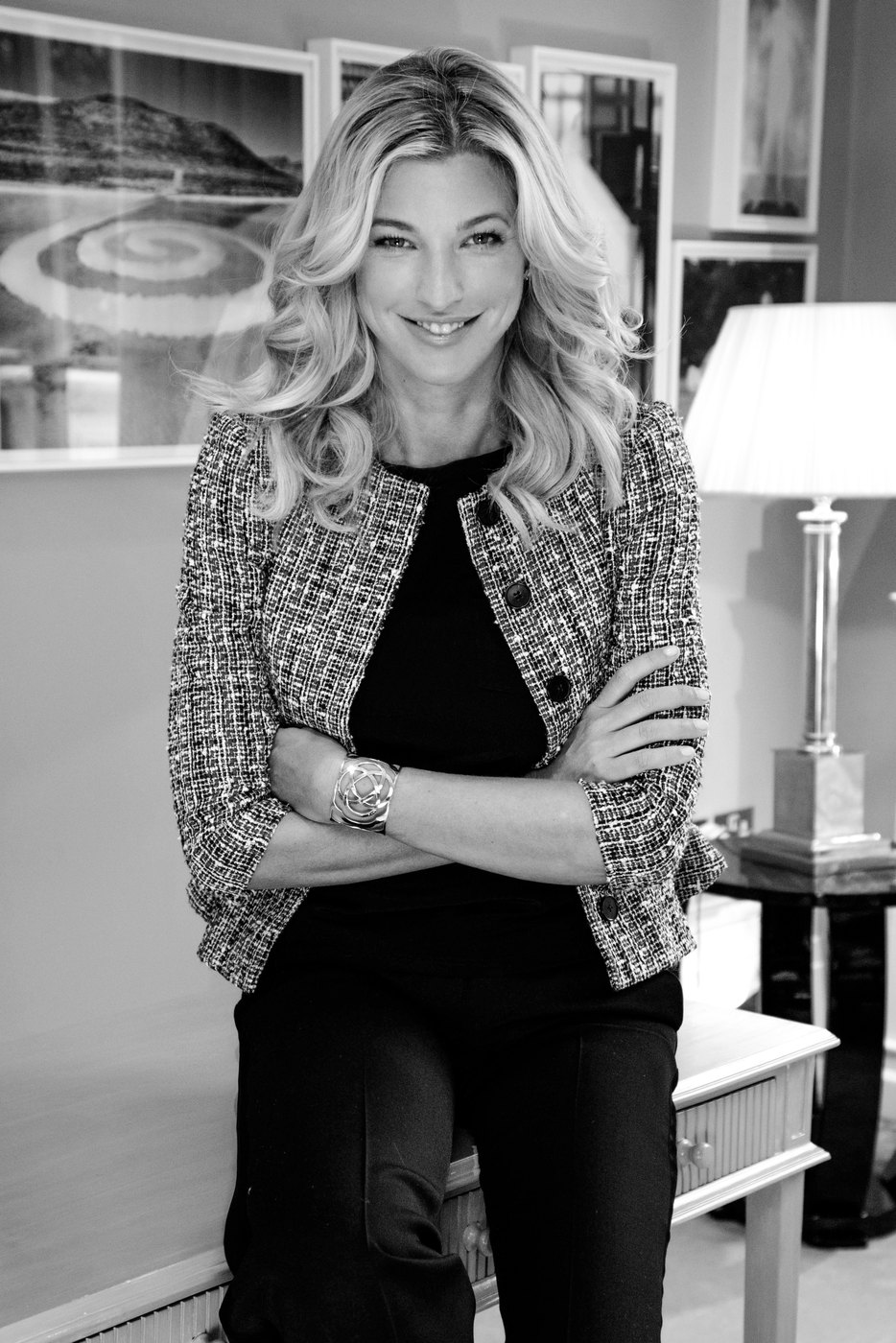 Nicole Junkerman in a tweed jacket, seated and smiling, in a black and white portrait