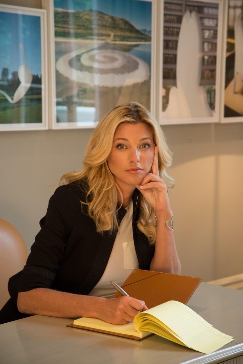 Nicole Junkerman writing in a notebook at a desk in warm light
