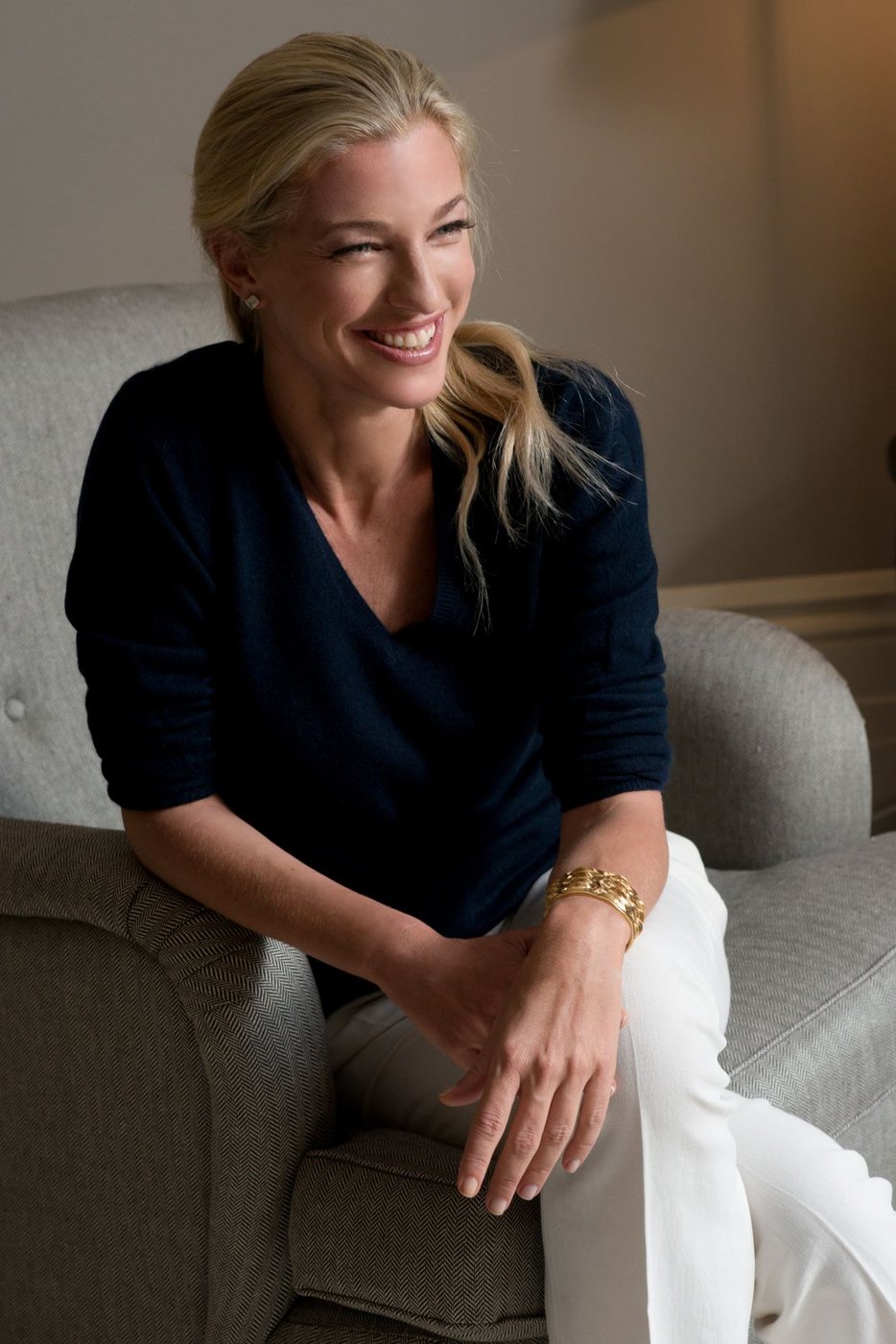 Nicole Junkerman seated in a soft armchair, smiling as she looks to one side
